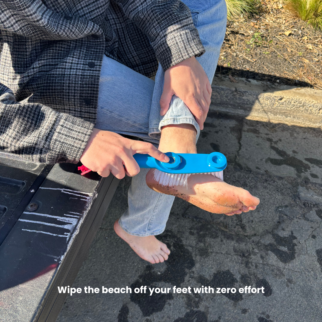 Person using blue foot brush tool to clean sand off feet after the beach