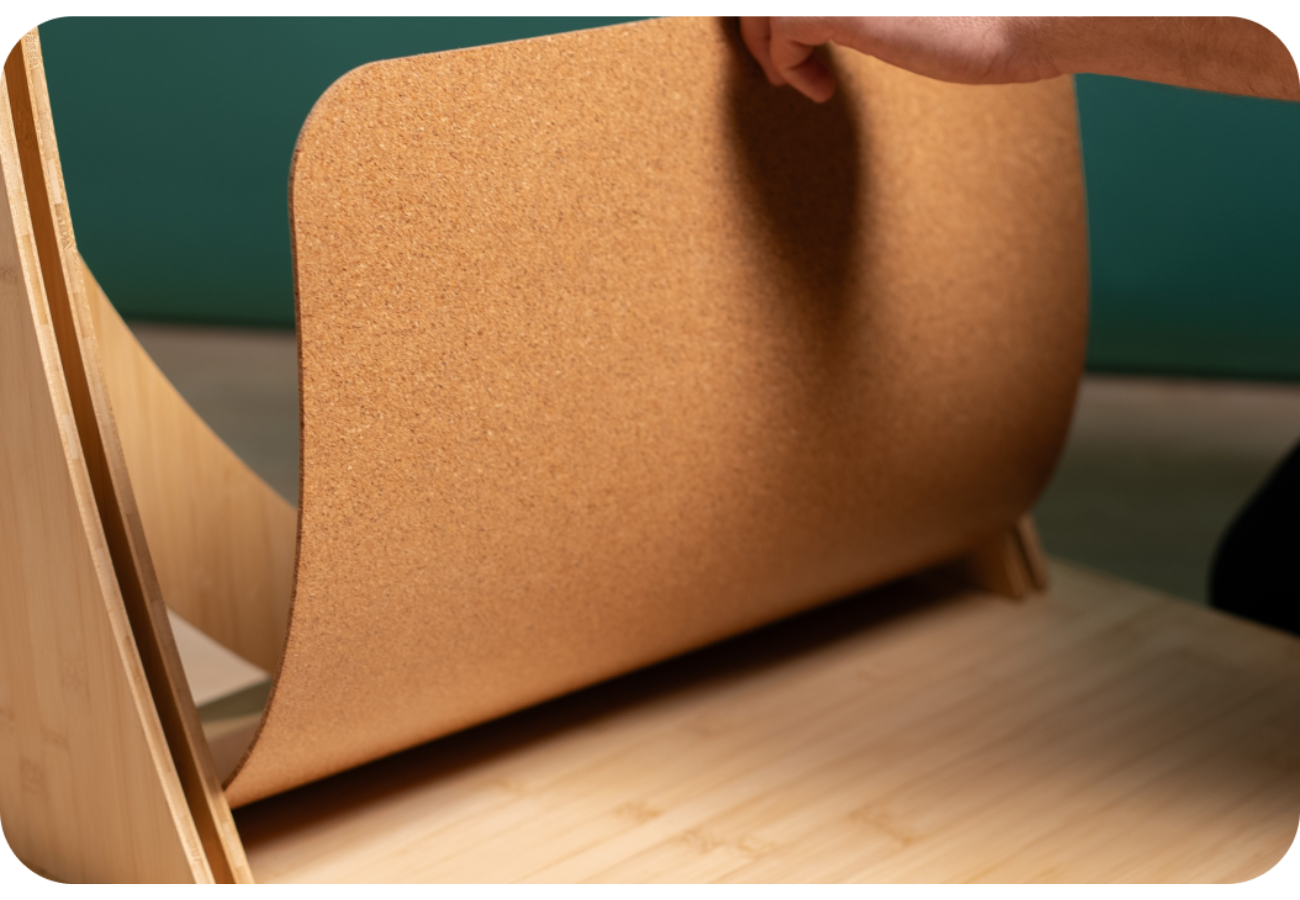 Hand lifting flexible cork sheet on wooden base, showing smooth curved design