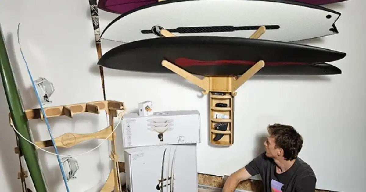 Man sitting near wall-mounted racks holding multiple surfboards in a storage room