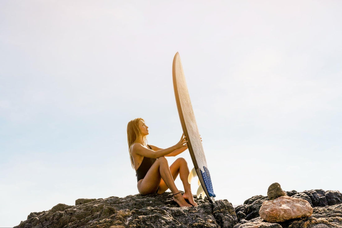 Surfer on the rocks holding her board