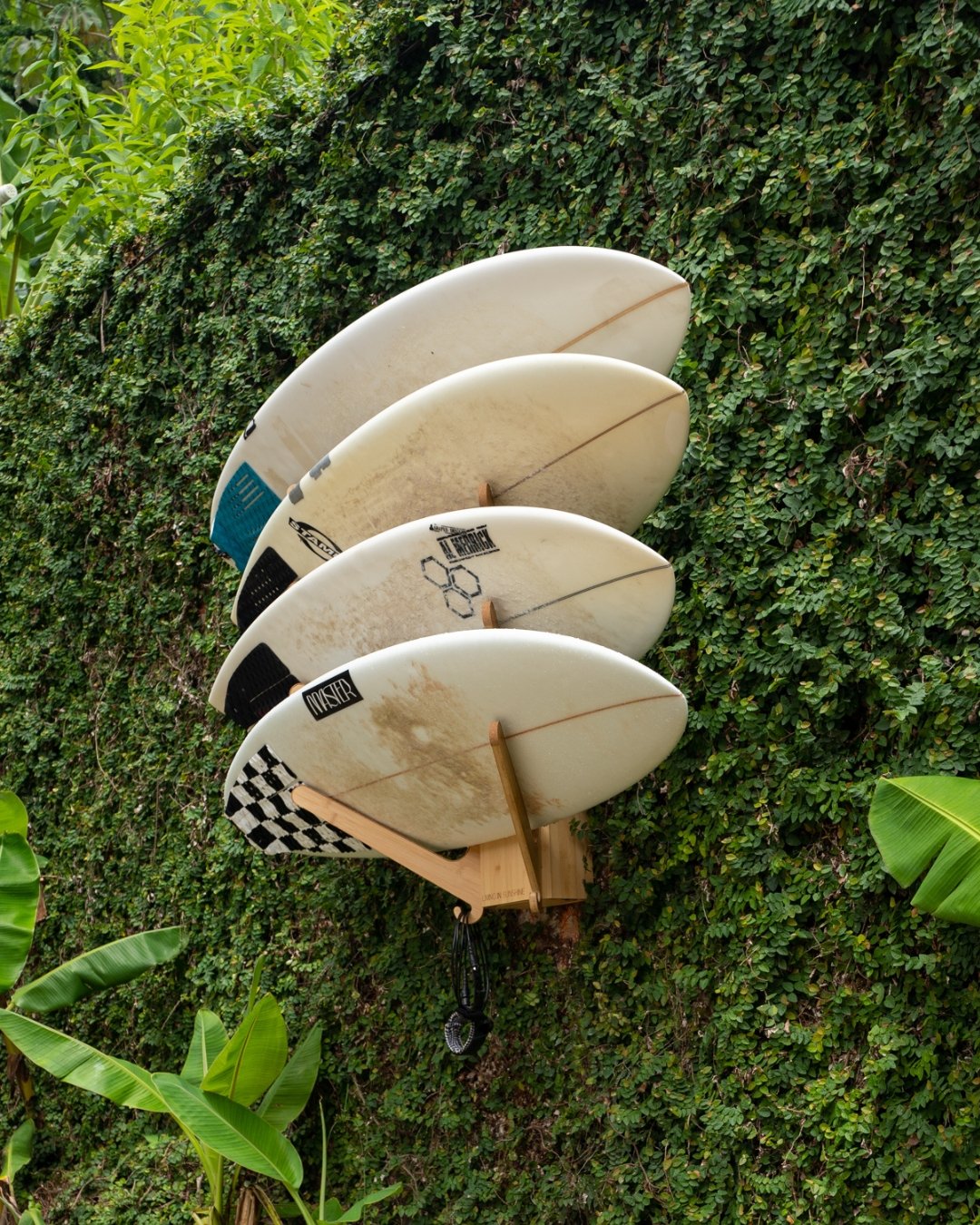 Four surfboards stored on the Sun Rack mounted to an outdoor garden wall, demonstrating durable construction and weather-resistant design.